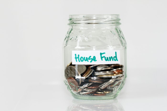 A glass jar of coins labelled House Fund