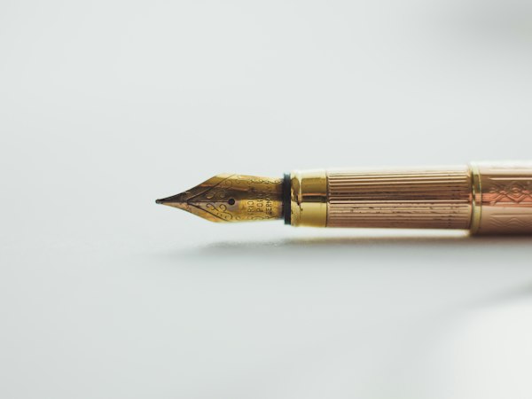 A gold fountain pen on a white desk