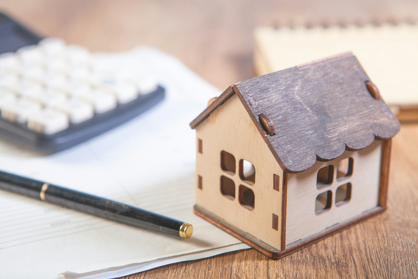A model house beside a calculator and a pen
