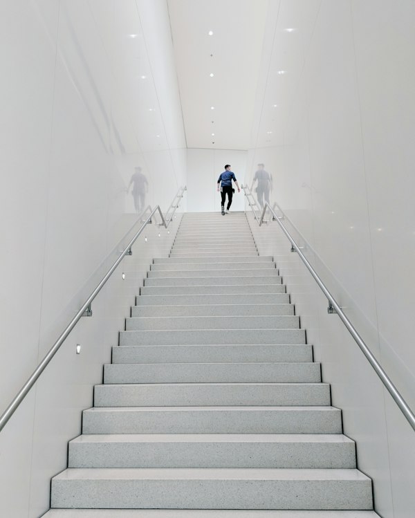 A person climbing a bright white staircase
