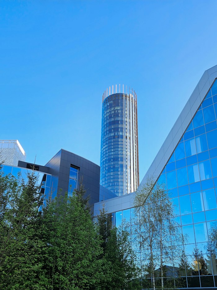 A glass corporate tower under a clear blue sky