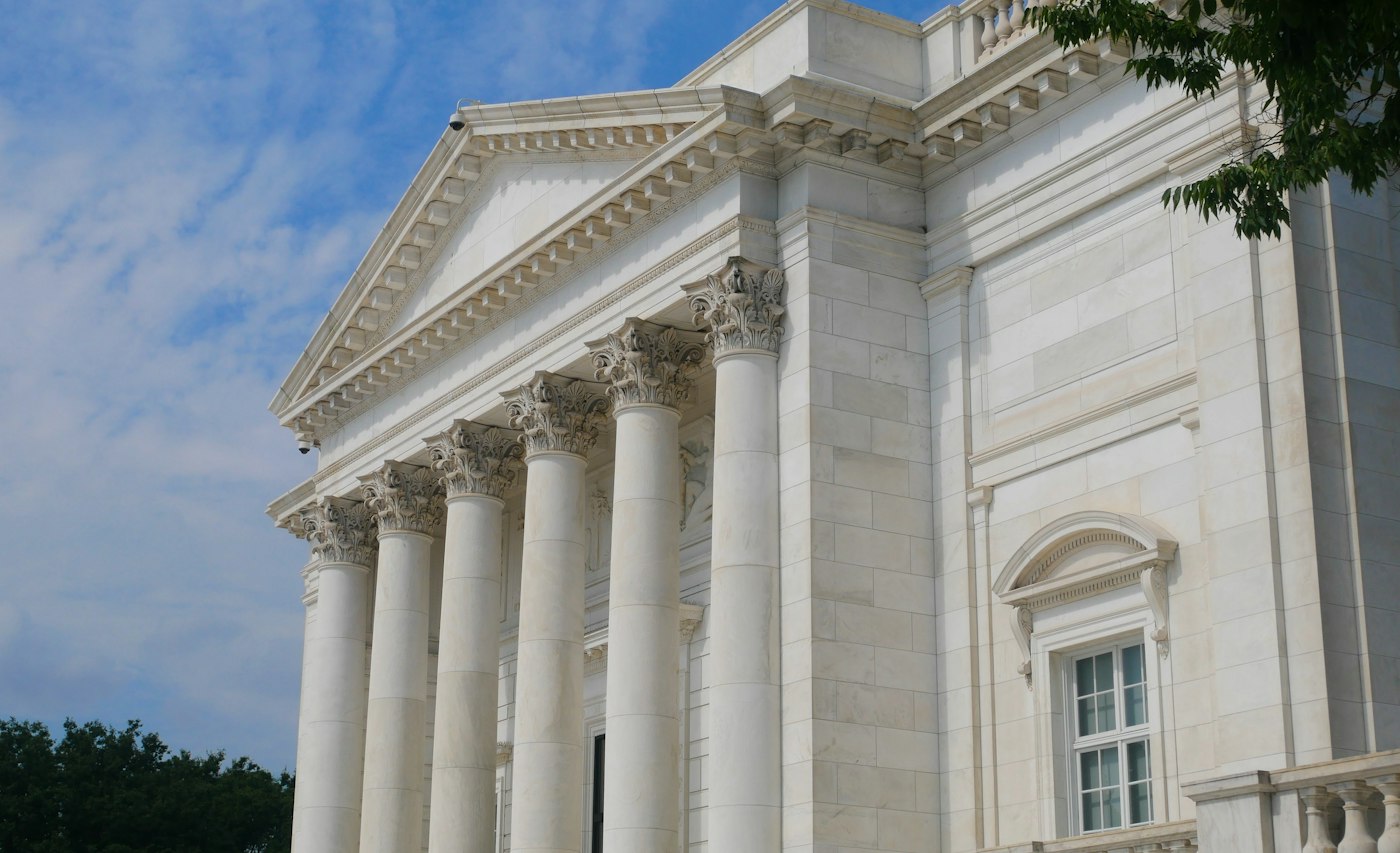 A white neoclassical building with columns under a blue sky