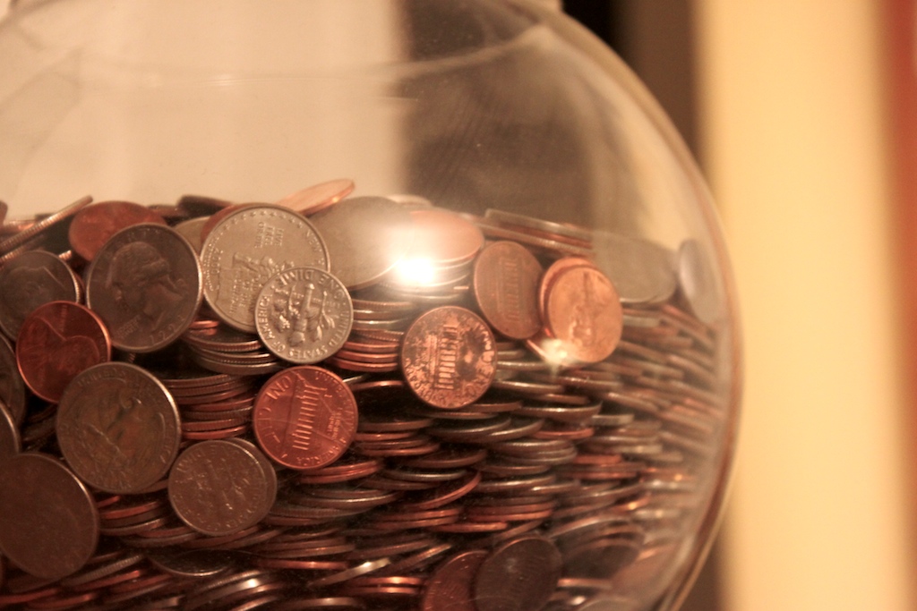 A glass jar almost full of coins