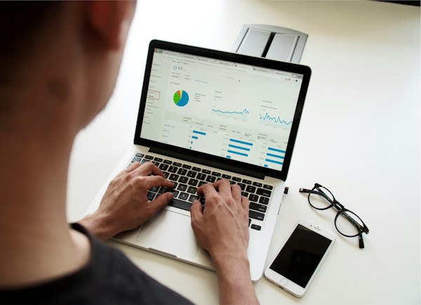 Hands on a laptop showing charts on a white desk