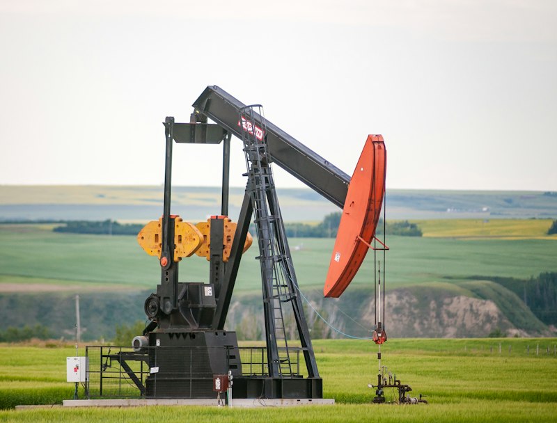 An oil pump jack in a green field in daylight