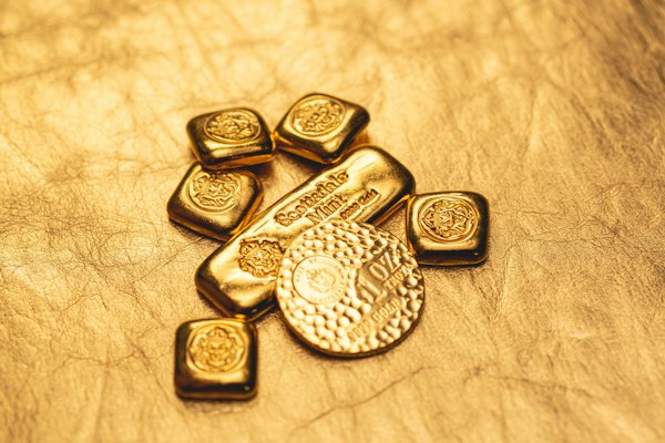 Small gold bars and coins on a golden surface