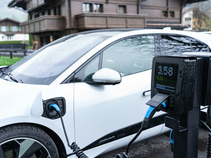 A white electric car charging at a station in daylight