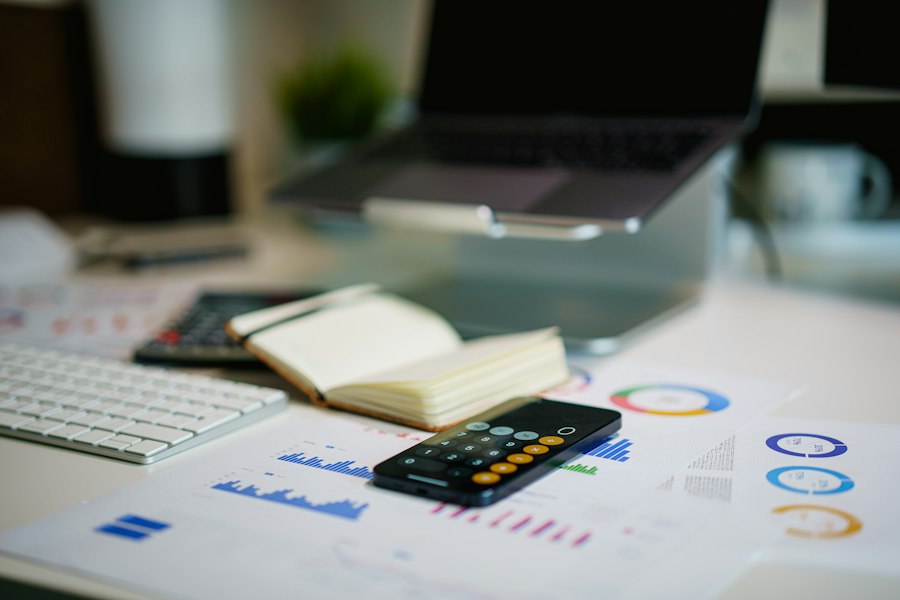 A laptop, a calculator and printed charts on a bright desk